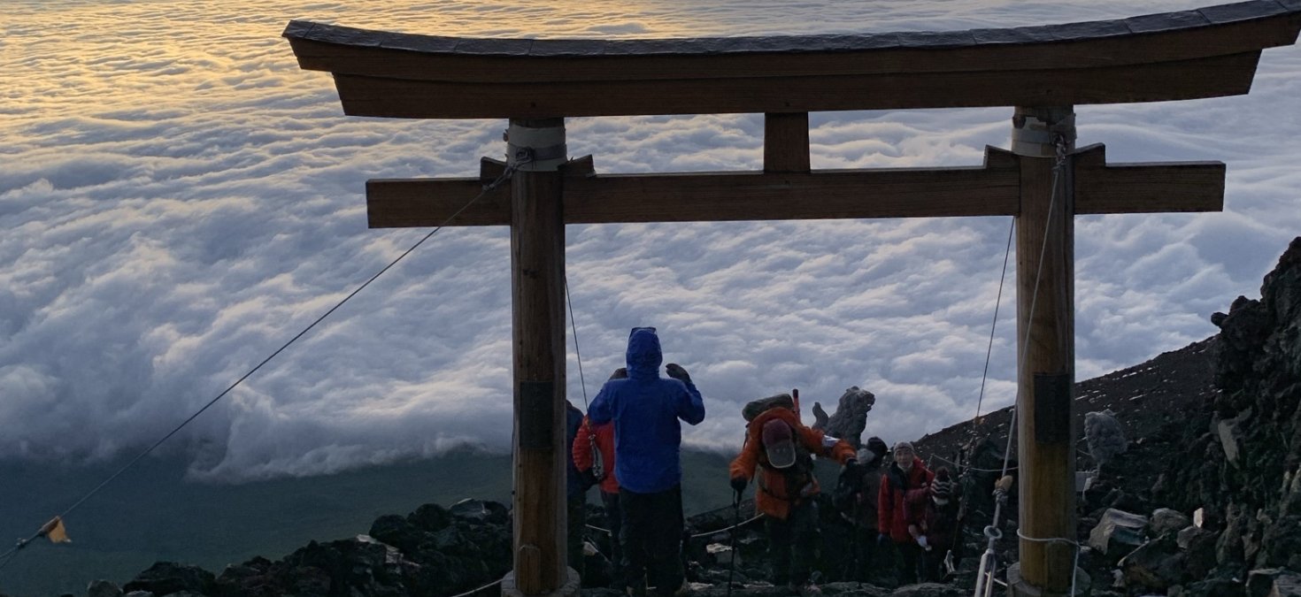 climbers on mt fuji under a torii gate